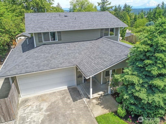 view of front of home featuring concrete driveway, a porch, and roof with shingles