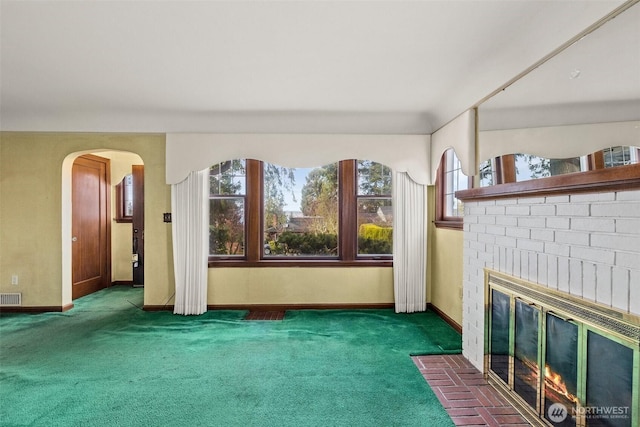 unfurnished living room featuring carpet, visible vents, baseboards, arched walkways, and a brick fireplace