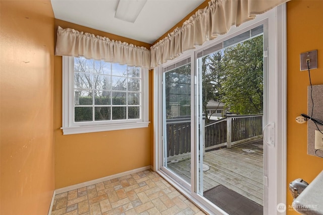 doorway to outside featuring baseboards and brick floor