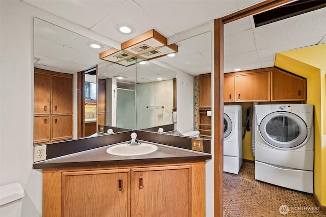 bathroom featuring washing machine and dryer, toilet, an enclosed shower, vanity, and a paneled ceiling