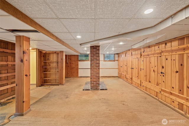 below grade area featuring wooden walls, recessed lighting, carpet floors, and a paneled ceiling