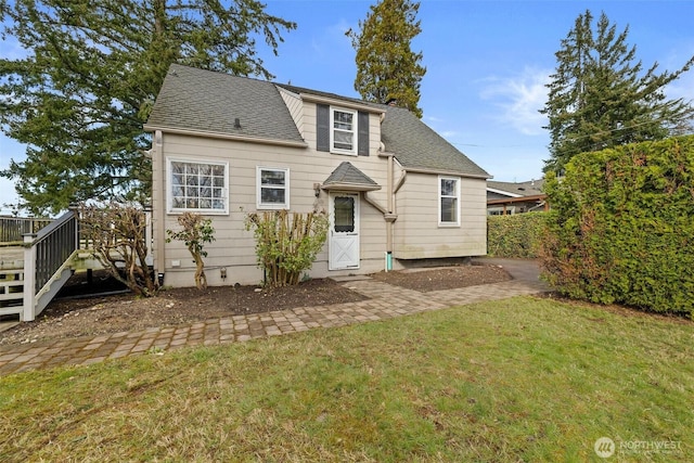 rear view of house with a lawn and a shingled roof