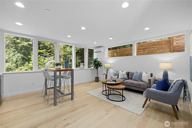 living area with light wood-style floors, baseboards, an AC wall unit, and recessed lighting