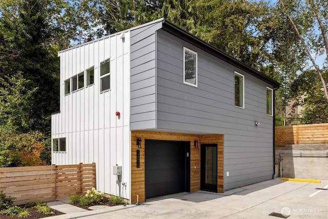 view of front facade with a garage, board and batten siding, and fence