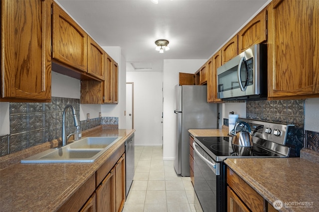 kitchen with stainless steel appliances, tasteful backsplash, a sink, and light tile patterned floors