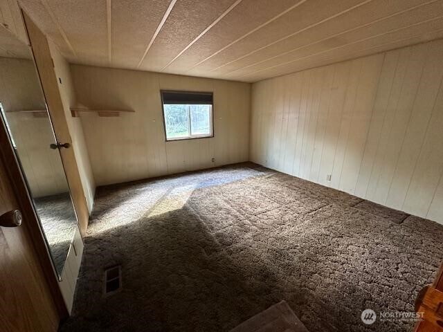 empty room with visible vents and carpet flooring