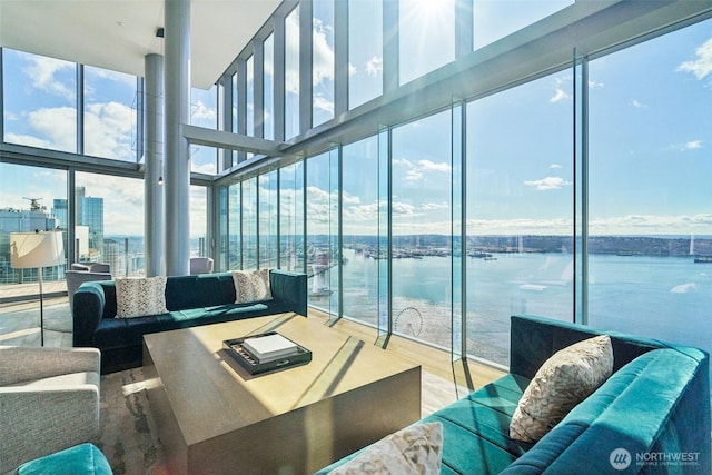 living area featuring floor to ceiling windows, wood finished floors, and a water view