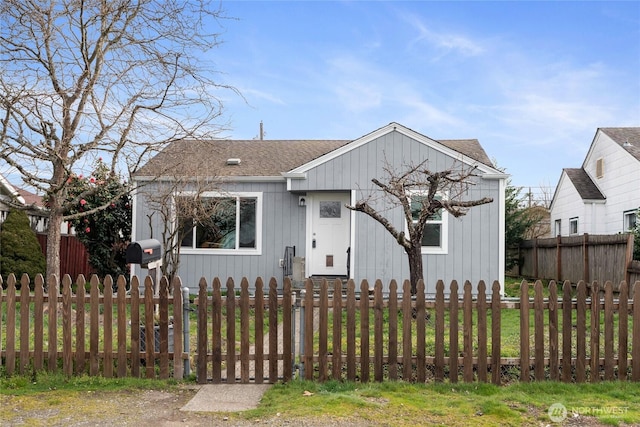 bungalow featuring roof with shingles and a fenced front yard