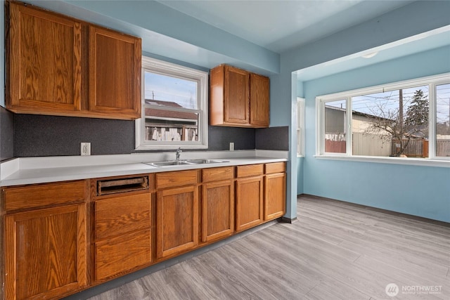 kitchen featuring brown cabinetry, light countertops, and a sink