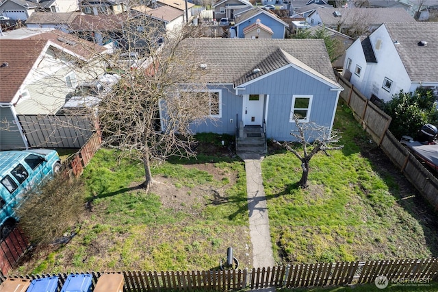 view of front facade featuring a shingled roof, fence private yard, and a residential view