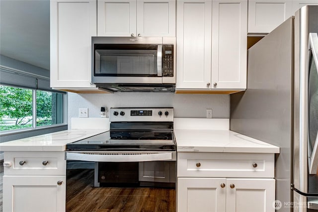 kitchen with stainless steel appliances, dark wood-type flooring, white cabinetry, and light stone counters