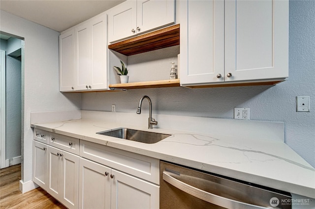 kitchen featuring light stone counters, light wood-style flooring, white cabinets, a sink, and dishwasher