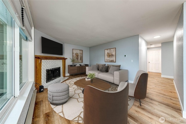 living area with a fireplace, light wood-style flooring, and baseboards