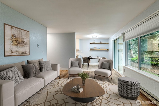 living area featuring a textured wall, baseboards, and wood finished floors