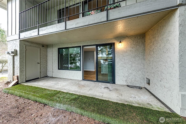 property entrance with a balcony and stucco siding