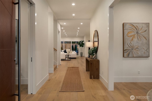 hallway featuring baseboards, light wood-type flooring, stairs, and recessed lighting