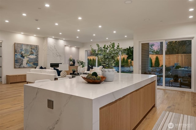 kitchen with a spacious island, modern cabinets, a premium fireplace, light wood-type flooring, and recessed lighting