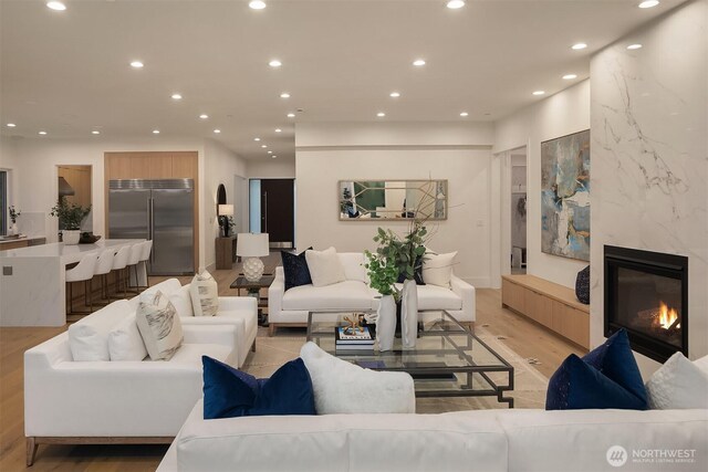 living area featuring a high end fireplace, recessed lighting, and light wood-style floors