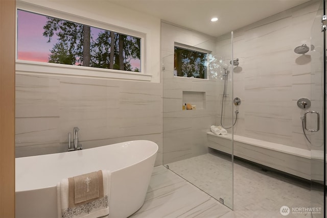 full bath featuring marble finish floor, a freestanding bath, tile walls, and an enclosed shower