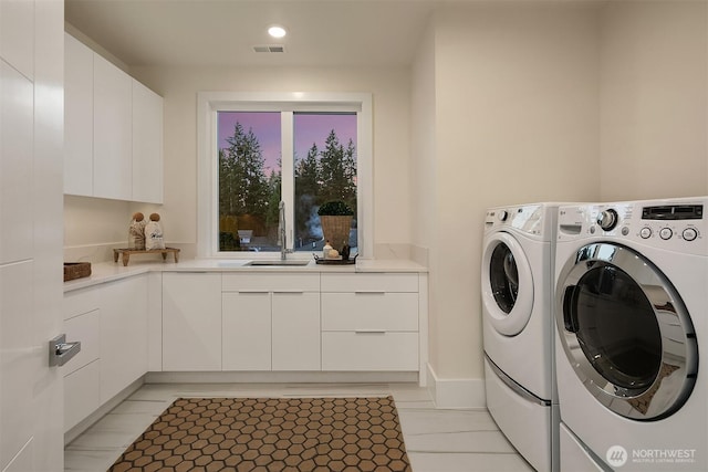 laundry room featuring light tile patterned floors, a sink, visible vents, washer and dryer, and cabinet space