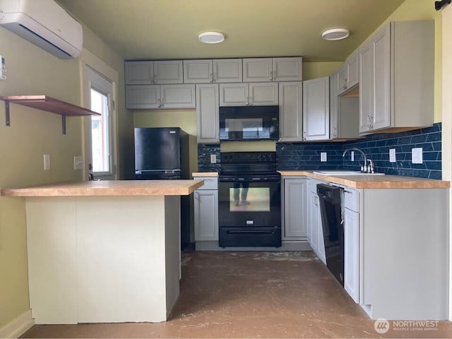 kitchen with tasteful backsplash, a wall mounted air conditioner, a peninsula, black appliances, and a sink