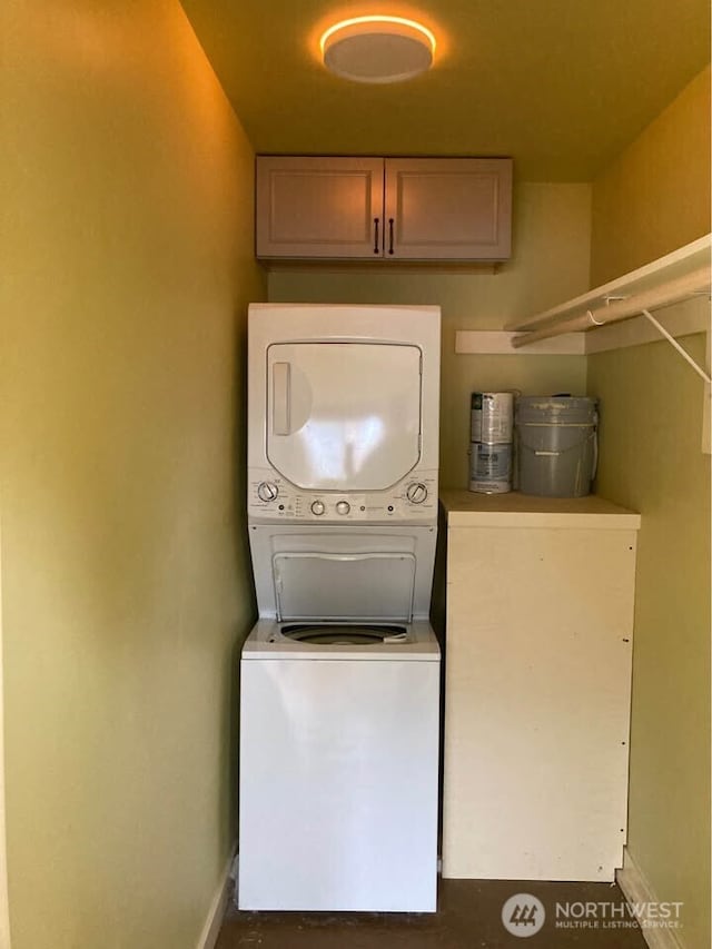 laundry area featuring stacked washer / drying machine and baseboards