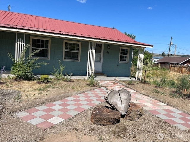 view of front of home with fence, covered porch, and metal roof