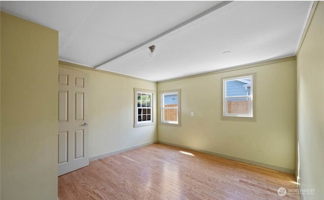 empty room featuring ornamental molding, baseboards, and wood finished floors