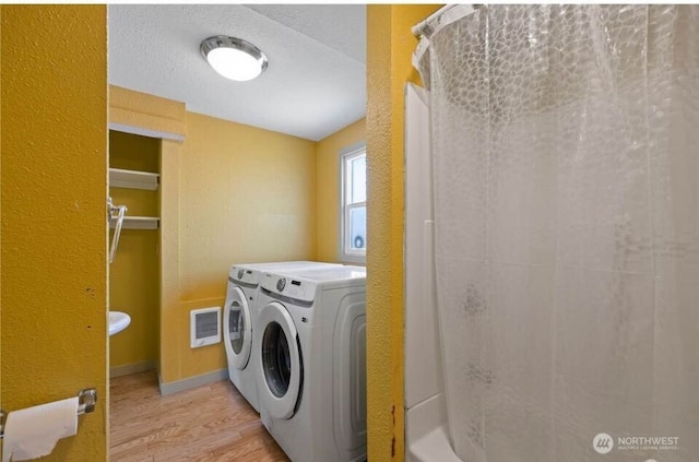 clothes washing area featuring wood finished floors, visible vents, baseboards, laundry area, and separate washer and dryer