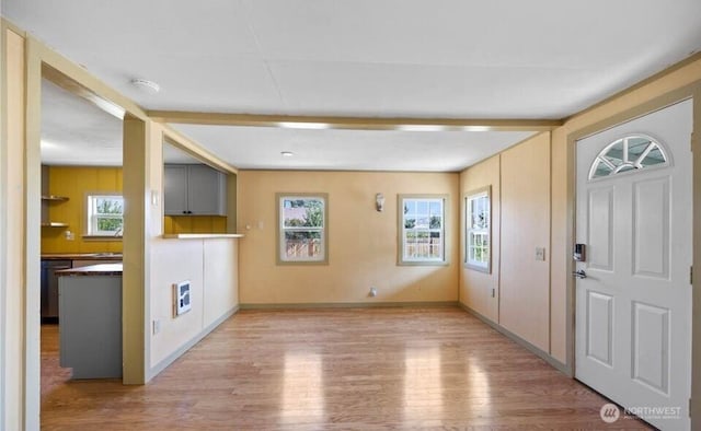 foyer featuring beam ceiling, heating unit, baseboards, and wood finished floors