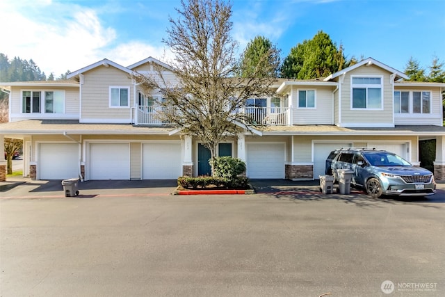 multi unit property featuring a garage, a balcony, and driveway