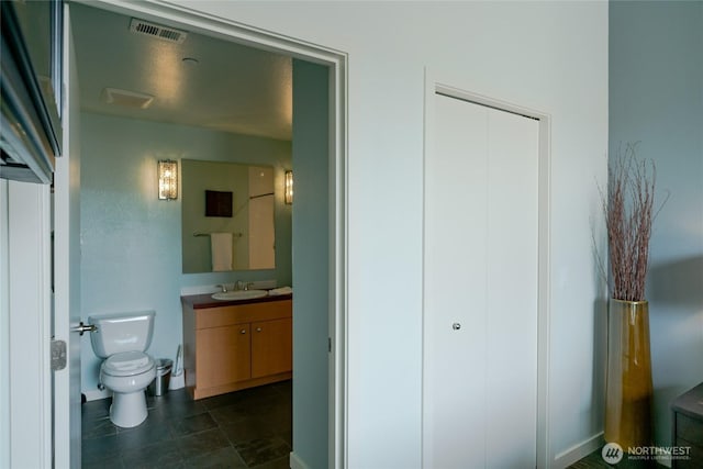 bathroom with toilet, vanity, and visible vents