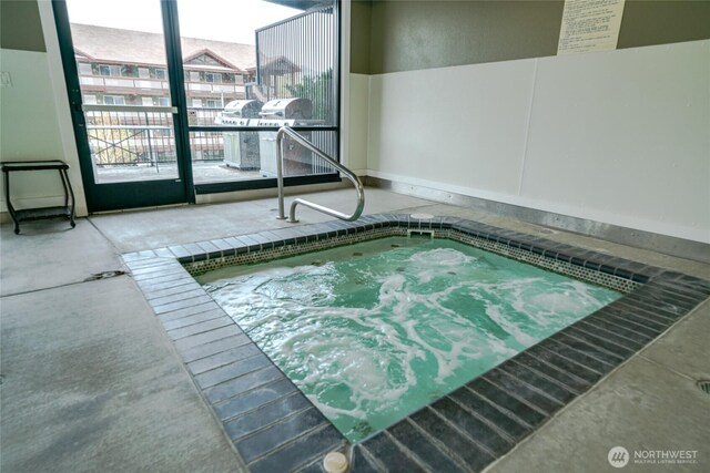 view of swimming pool with an indoor hot tub and a grill