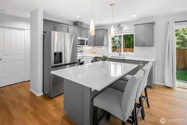 kitchen with light wood-style floors, gray cabinets, appliances with stainless steel finishes, and a sink