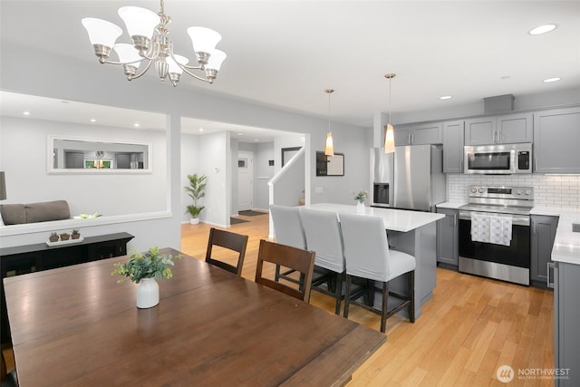 dining space with recessed lighting, a chandelier, stairs, and light wood finished floors