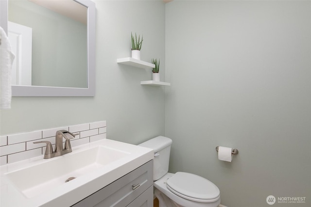 half bathroom with vanity, toilet, and backsplash