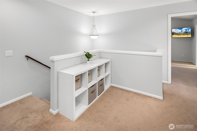 corridor with an upstairs landing, light carpet, and baseboards