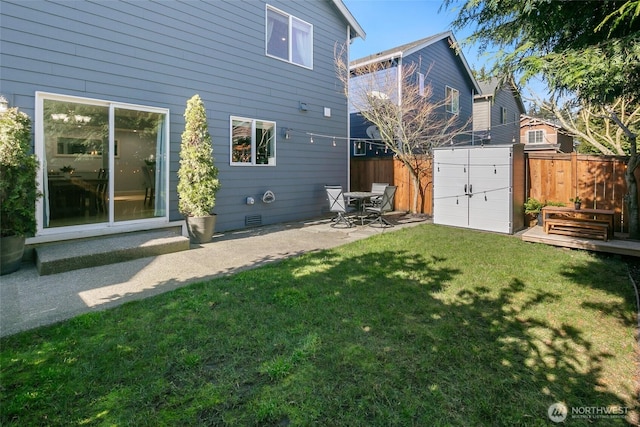 rear view of property with an outbuilding, a storage unit, a fenced backyard, and a yard