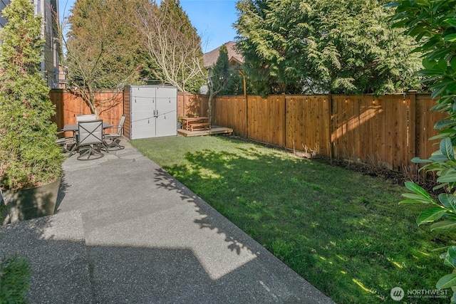 view of yard with an outdoor structure, a fenced backyard, a shed, and a patio area