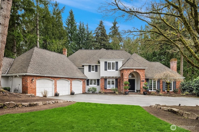 view of front of house featuring driveway, a front yard, an attached garage, brick siding, and a chimney