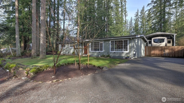 view of front of property with crawl space, a detached carport, a front yard, and aphalt driveway