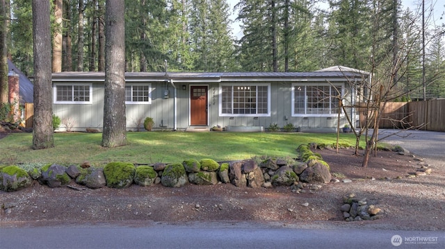 ranch-style house featuring metal roof, a front lawn, and fence