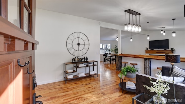 living room featuring light wood-type flooring, lofted ceiling, and baseboards