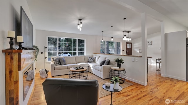 living area featuring light wood-type flooring, baseboards, and a fireplace