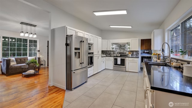 kitchen featuring a sink, tasteful backsplash, dark countertops, stainless steel appliances, and wall chimney range hood