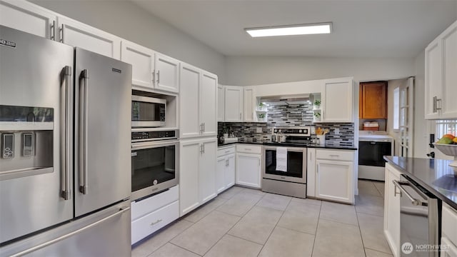 kitchen with dark countertops, appliances with stainless steel finishes, washer / clothes dryer, and wall chimney range hood