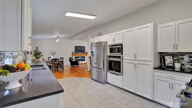 kitchen featuring dark countertops, backsplash, white cabinets, and stainless steel appliances