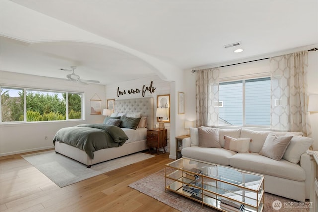 bedroom featuring arched walkways, visible vents, baseboards, and wood finished floors