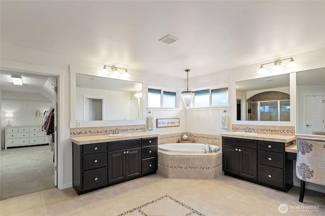 full bath featuring two vanities, a stall shower, a sink, tile patterned flooring, and a garden tub