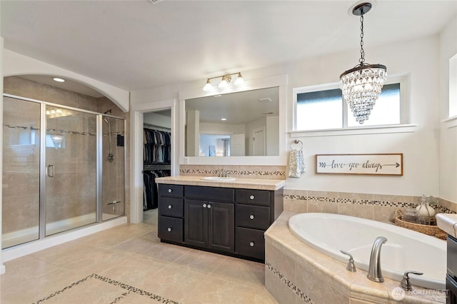 bathroom with vanity, tile patterned flooring, a shower stall, a spacious closet, and a garden tub